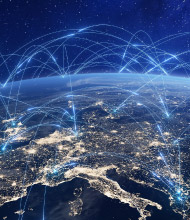 Nighttime view of Europe from space with city lights and overlaid glowing lines and nodes representing interconnected communication networks.