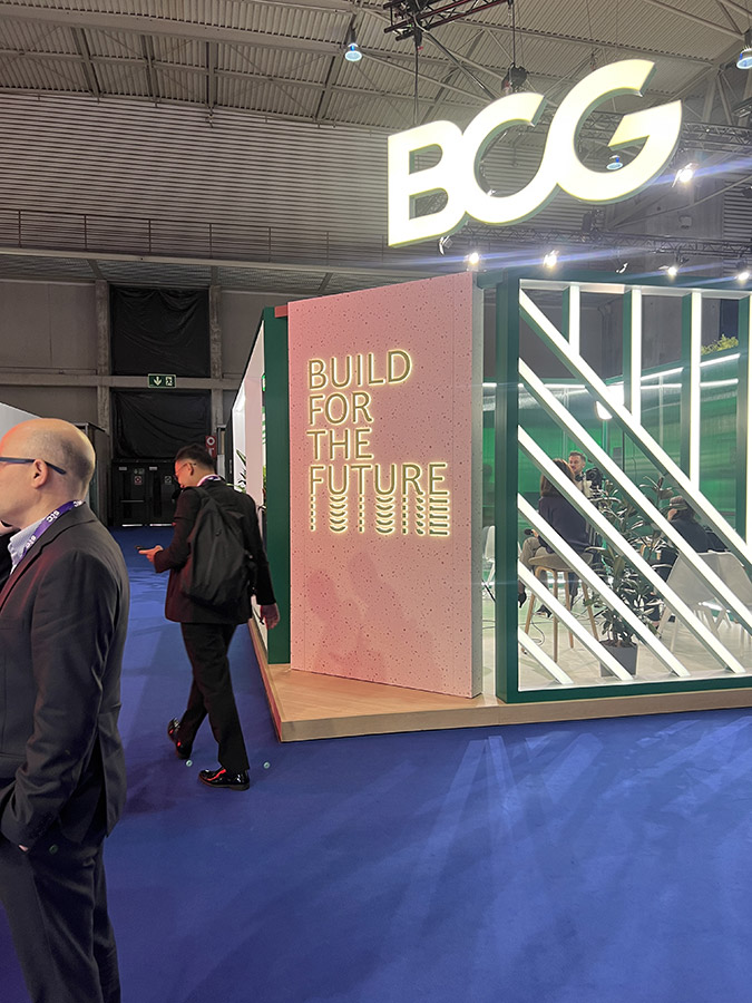 A side view of the BCG exhibit with a large 'BUILD FOR THE FUTURE' slogan on a pink background.