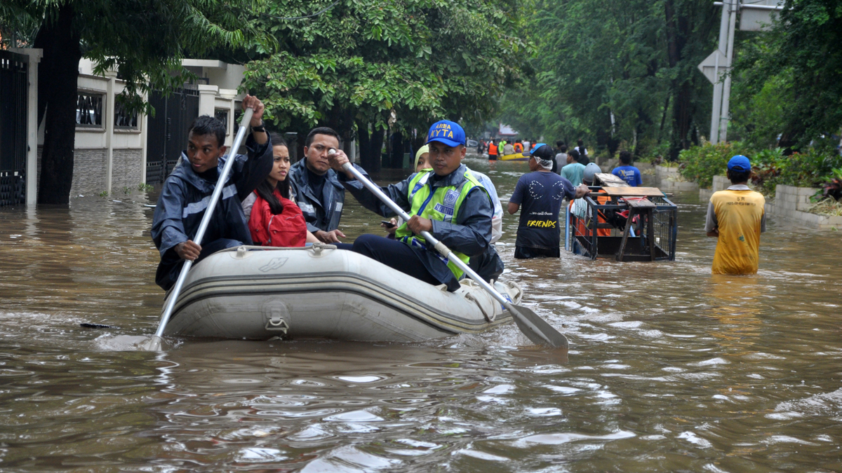 Residents of Jakarta navigate a flooded street using a rubber boat after heavy rains caused significant flooding in the area.
