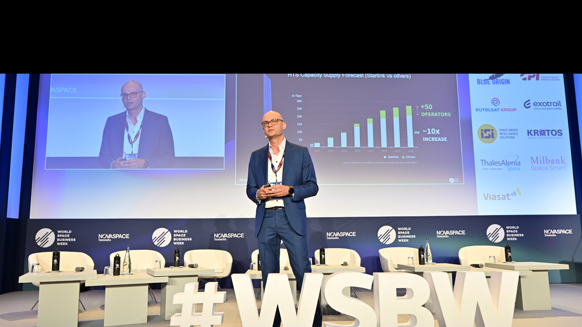 Speaker at World Space Business Week presenting a chart on HTS capacity supply forecast, comparing Starlink with other satellite operators.