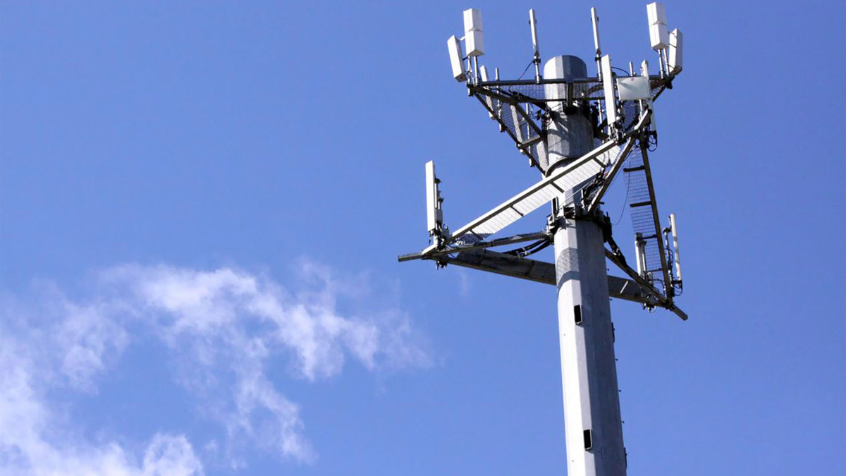 A tall telecommunications tower with multiple antennas against a clear blue sky.