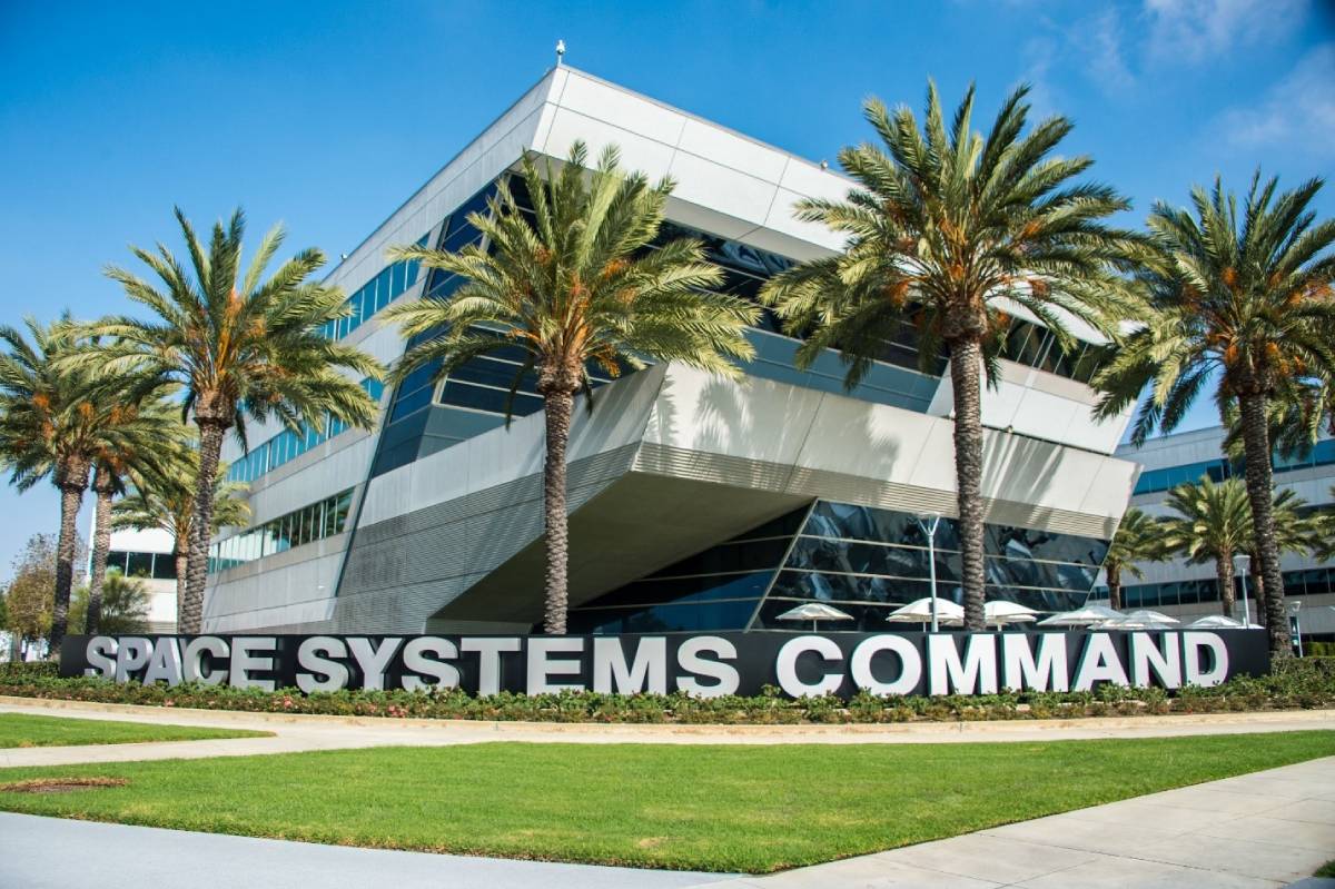 Modern angular building with palm trees in front and large signage reading 'Space Systems Command.'