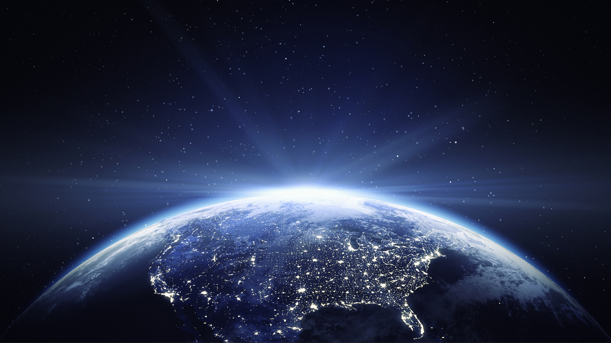 Earth viewed from space at twilight over North America, the curved limb glowing with atmosphere and city lights visible across the continent.