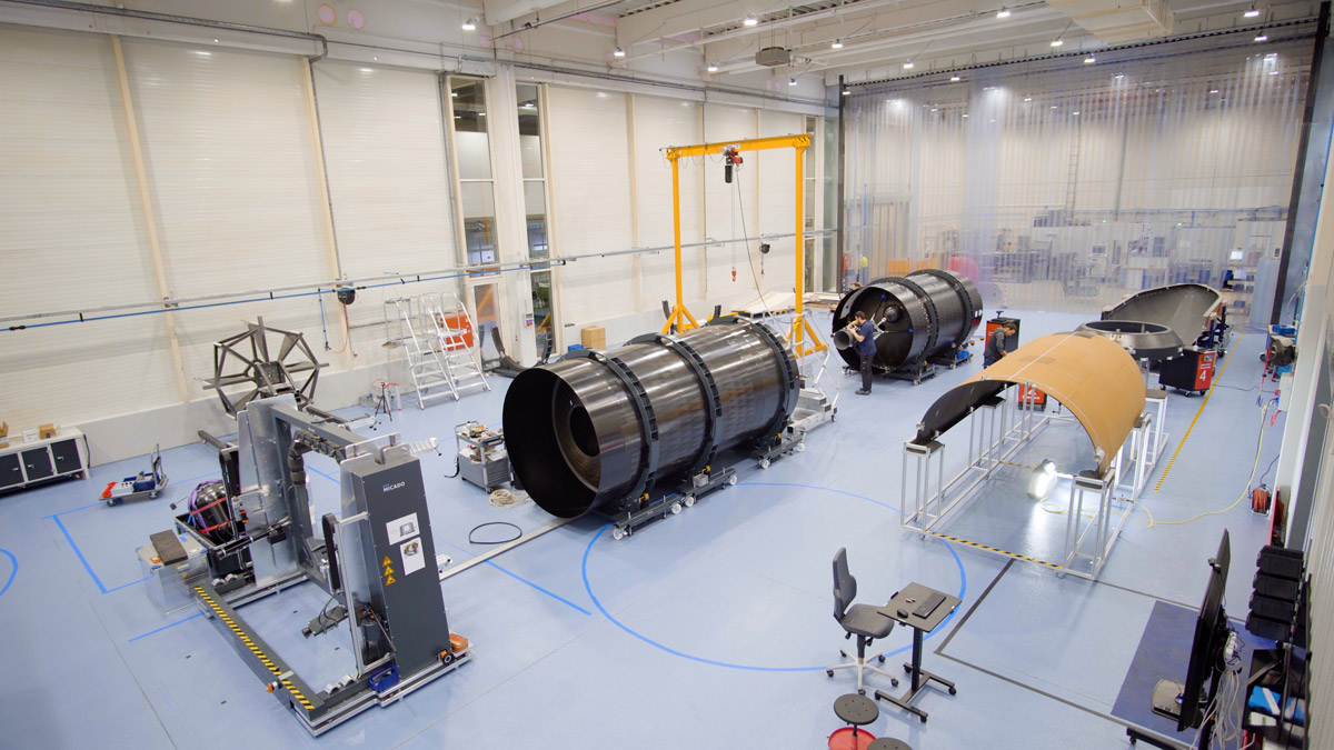 Isar Aerospace Spectrum rocket under assembly in high-tech facility with cylindrical components, precision machinery, and engineers at work during manufacturing stage.
