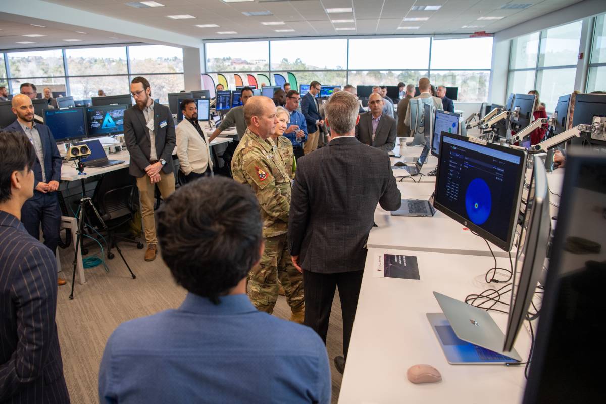 Lt. Gen. Douglas A. Schiess and Chief Master Sgt. Tina Timmerman visit the Space Domain Awareness TAP Lab facility and observe people working at computer stations. (Source: USSF/Tiana Williams)