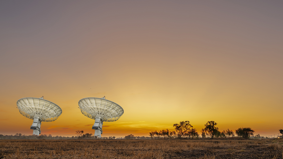 Two ground station antennas at sunset, symbolizing GSaaS infrastructure.