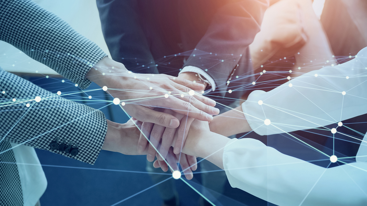Close-up of several hands stacked together, overlaid with a digital network graphic representing teamwork and connection.