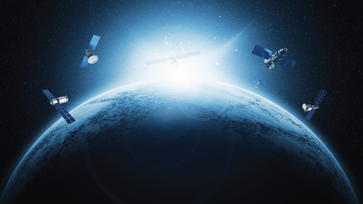 View of a partially sunlit Earth with multiple solar-panelled satellites orbiting against a starry background.