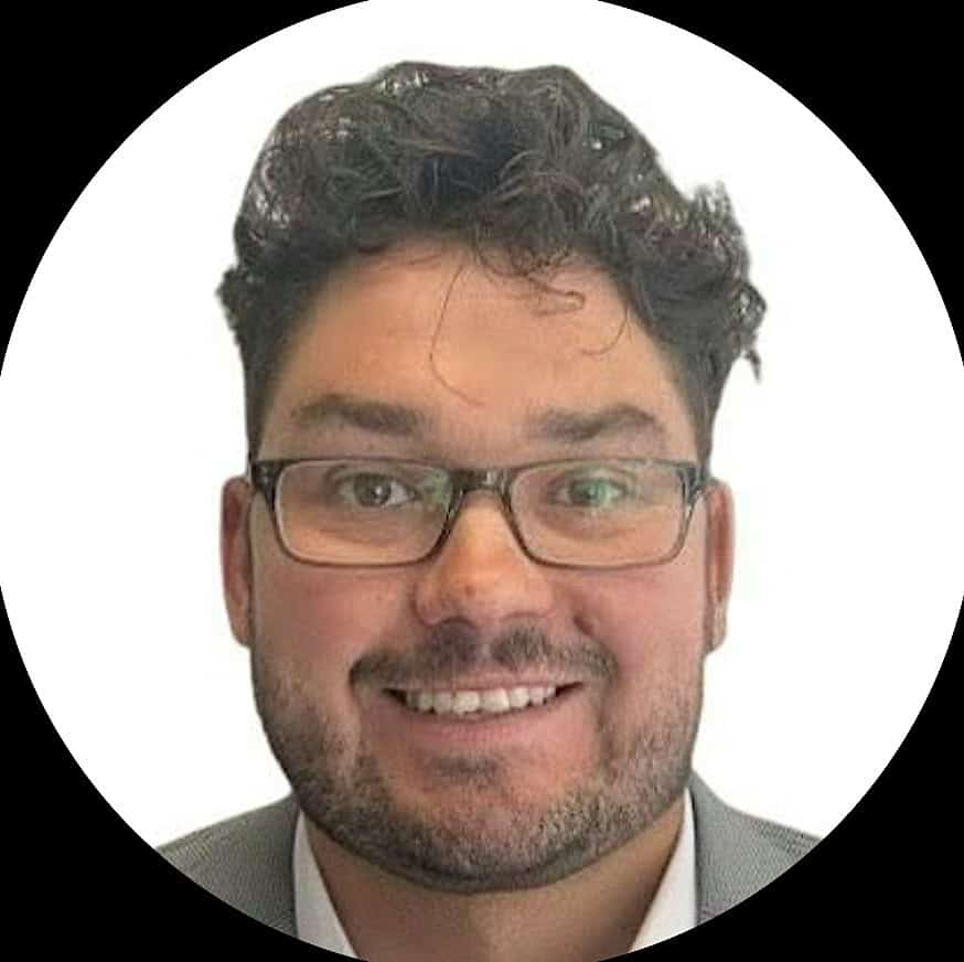 A smiling man with dark hair and glasses.