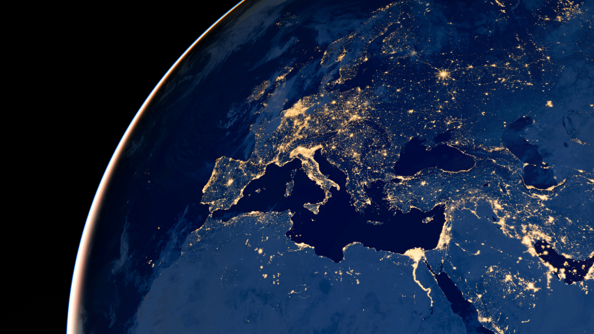 A satellite view of Earth at night, showing the illuminated city lights of Europe and Northern Africa.
