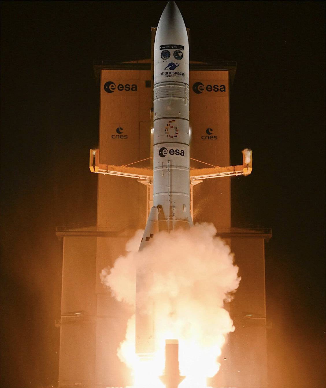 Ariane 6 rocket liftoff at Europe’s Kourou launch pad on August 12, 2025, engines blazing with bright flames and smoke, featuring ESA, CNES and Arianespace logos.