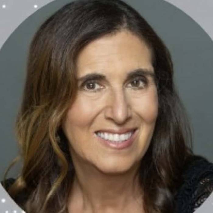 Head-and-shoulders portrait of Jennifer Manner, AST senior vice president for regulatory affairs and international strategy, smiling with long dark brown hair with lighter highlights against a dark gray background framed by a circular border with small white dots.