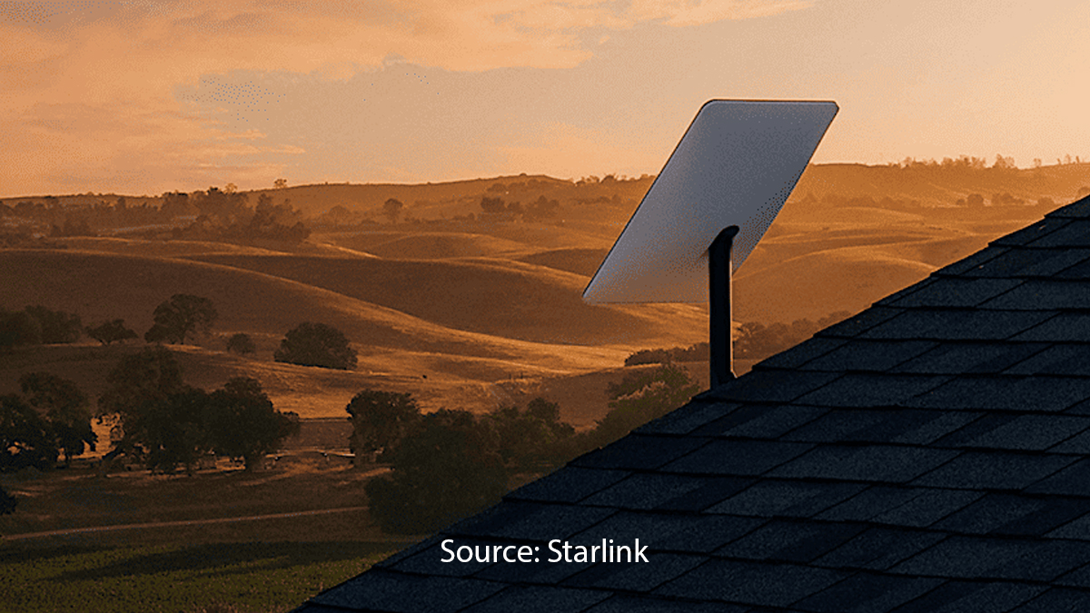  A Starlink satellite dish installed on a rooftop, with a scenic countryside view of rolling hills and trees at sunset.