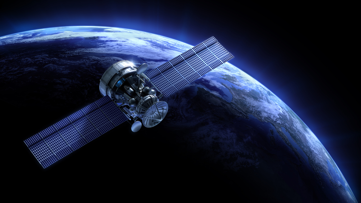 A spacecraft with large solar panels orbits above Earth against the dark backdrop of space.