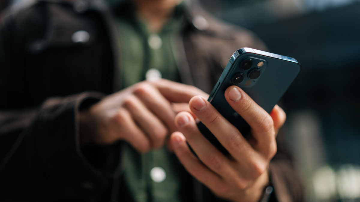 A close-up shot of a person holding a modern smartphone, showcasing its rear camera lenses as they interact with the device.