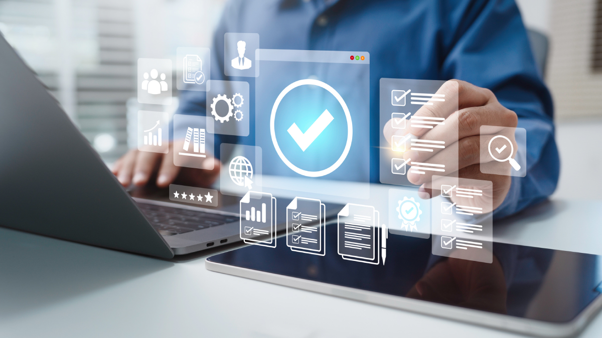 Person using laptop and tablet with digital overlays of checklists, gears, and a large checkmark icon for certification.