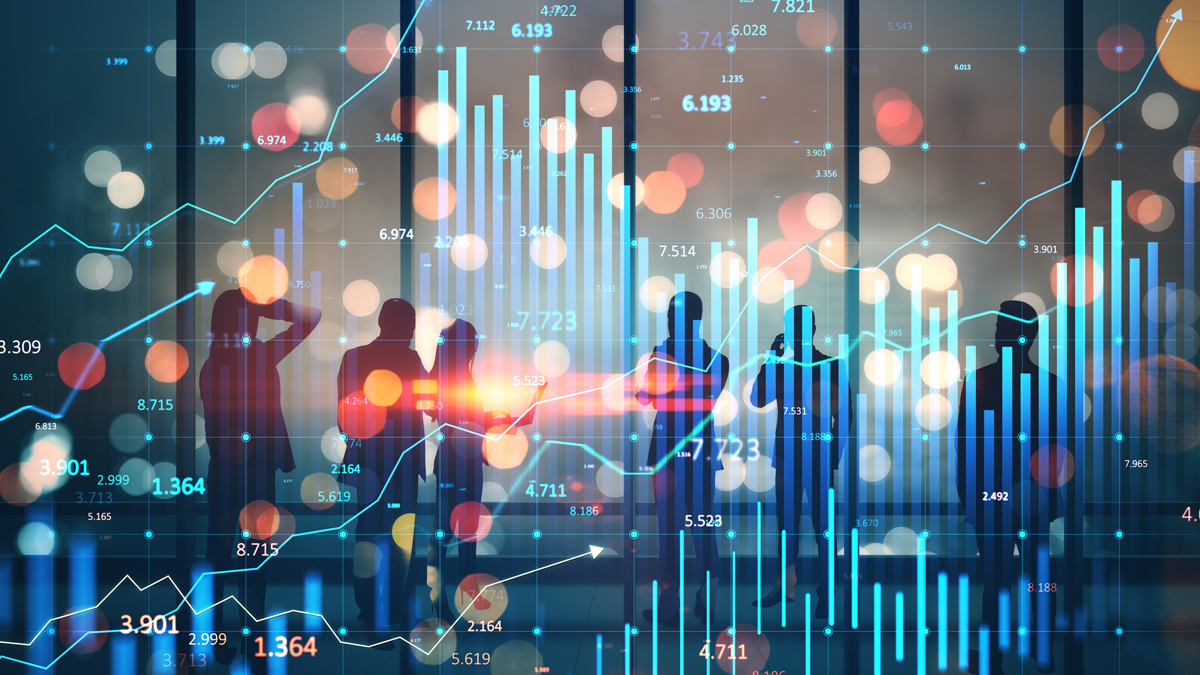 Silhouetted business professionals observe dynamic financial bar charts and upward-trending lines overlaid with blurry light bokeh, symbolizing shifting economic trends and capital flows.