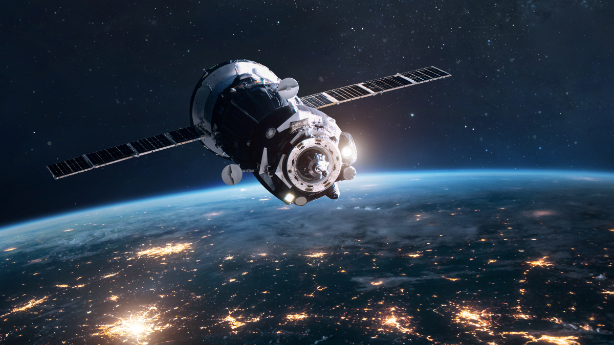 A digital rendering of a satellite orbiting high above the Earth, with the planet's surface glowing with city lights against the dark backdrop of space.