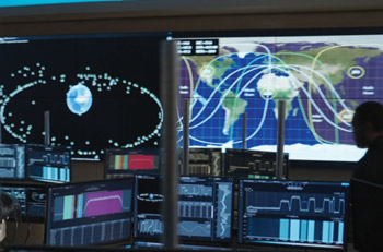 High-tech control room with multiple monitors displaying satellite tracking data, global maps, and Earth orbit diagrams, illustrating advanced space monitoring and aerospace operations.