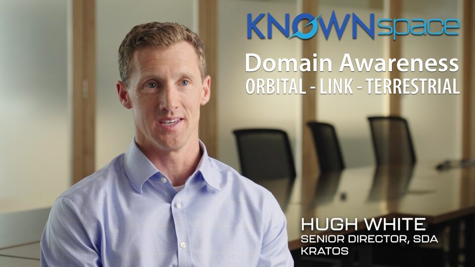 Hugh White, Senior Director of SDA at Kratos, speaking in front of KnownSpace logo and video overlay text reading Domain Awareness ORBITAL LINK TERRESTRIAL.