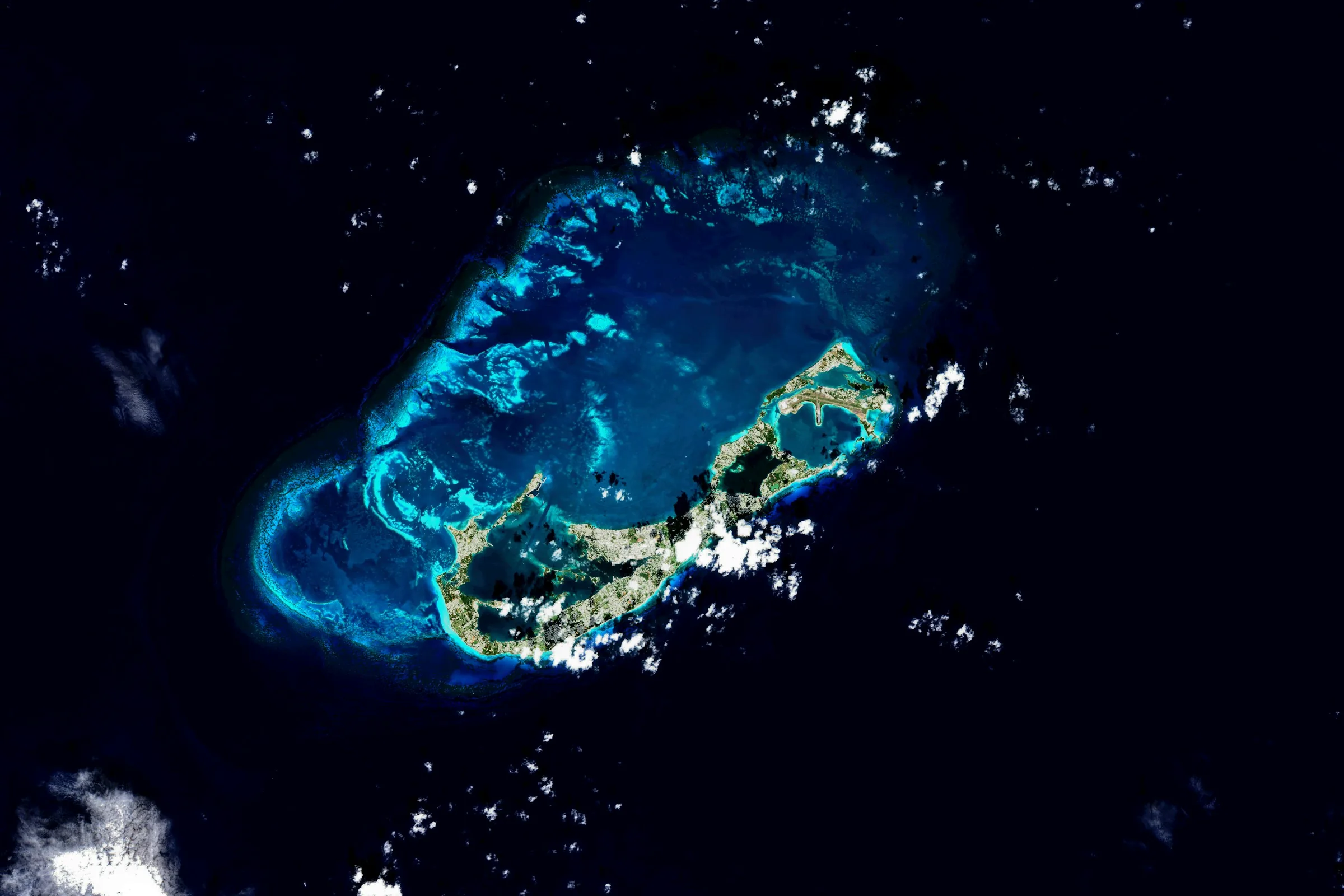 A series of large satellite tracking ground stations deployed in a scenic, remote landscape under a bright blue sky.