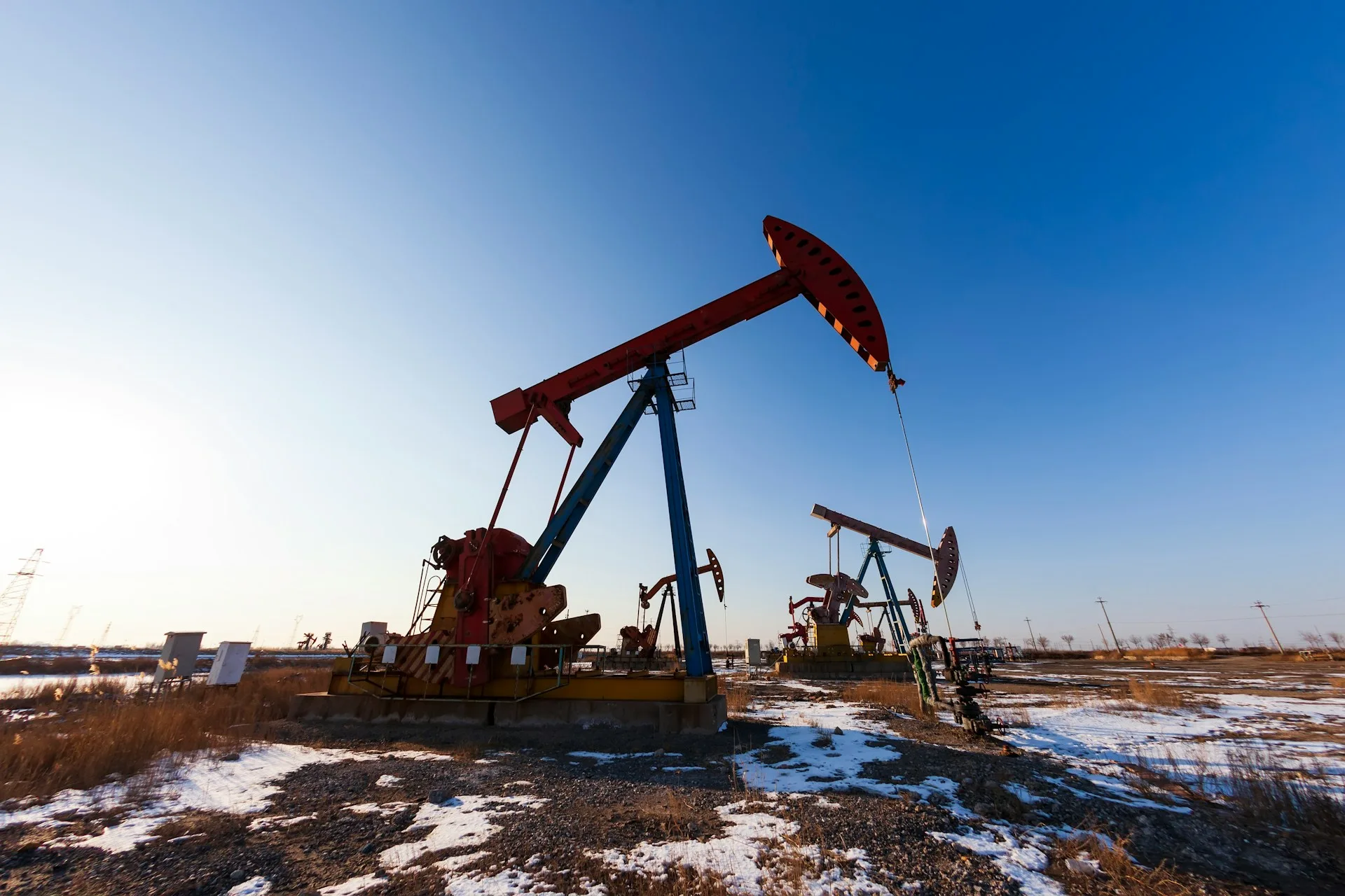 Oil pumpjacks operating under blue sky in remote industrial field