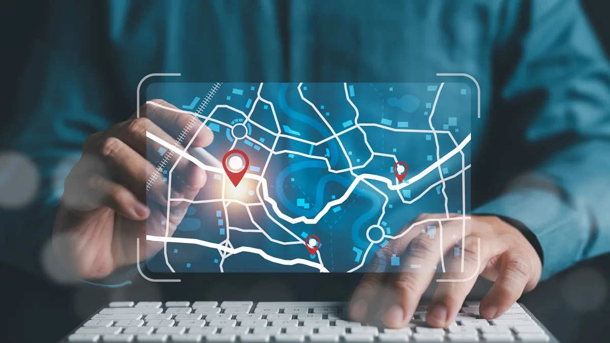 Person using a futuristic transparent map interface with red location markers, interacting via a keyboard.