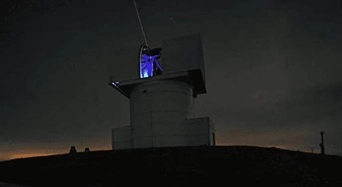 The optical ground station at the National Observatory of Athens, with a laser beam emitting from its telescope dome against a night sky.