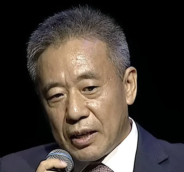Zhigang Bian, vice chairman of the China National Space Administration, speaks into a microphone during a formal event, dressed in a suit and tie.