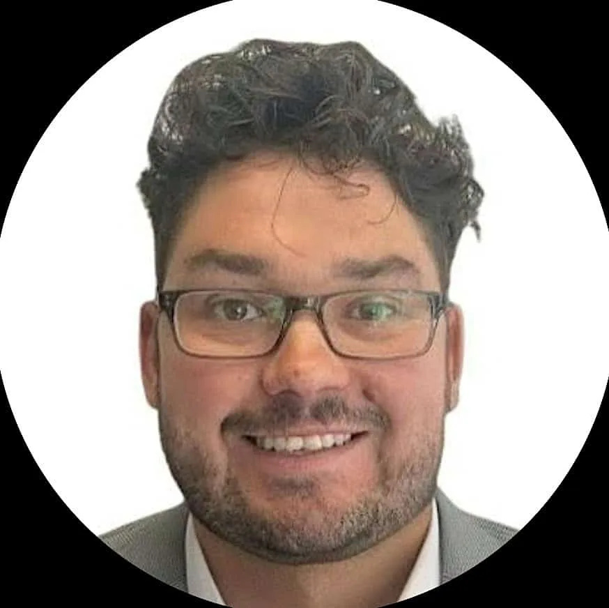 A smiling man with dark hair and glasses.