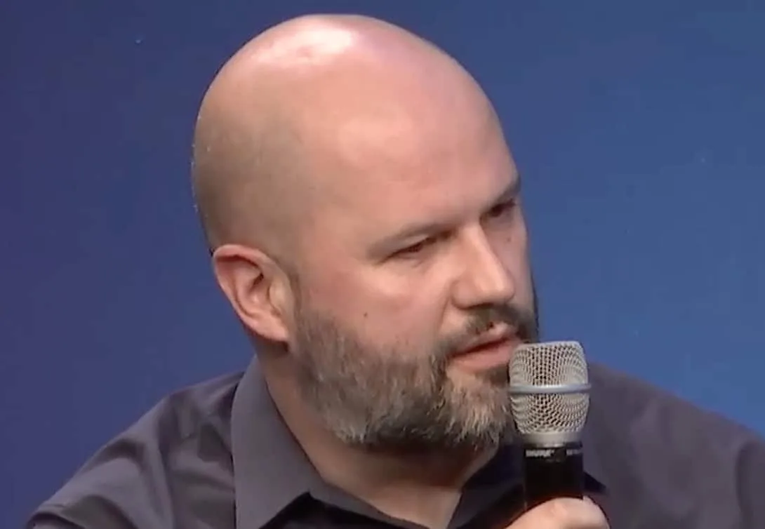 Mersad Cavcic, Globalstar chief product officer, speaking into a handheld microphone against a solid blue background.