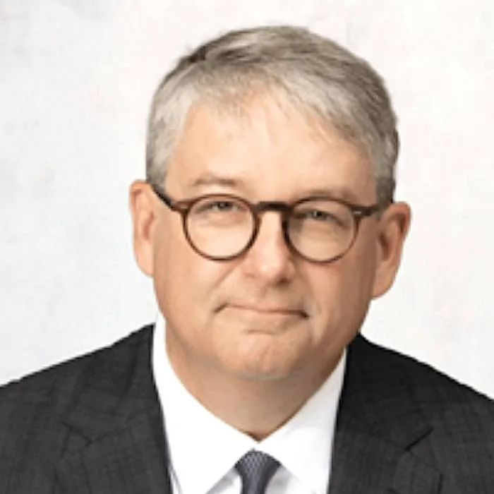 Head-and-shoulders portrait of Barbee Ponder, Globalstar's general counsel, with short gray hair and round eyeglasses wearing a dark checkered suit, white shirt, and dark tie against a plain light background.