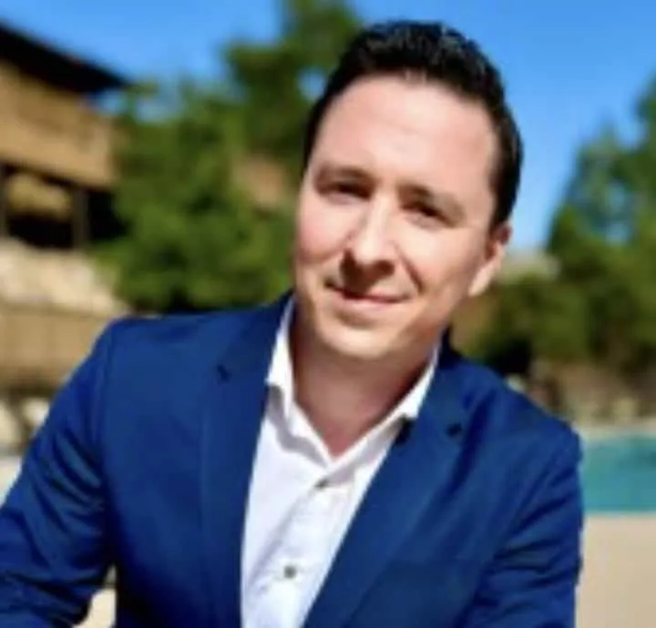 Jordan Vannitsen smiling in a blue suit, outdoors.