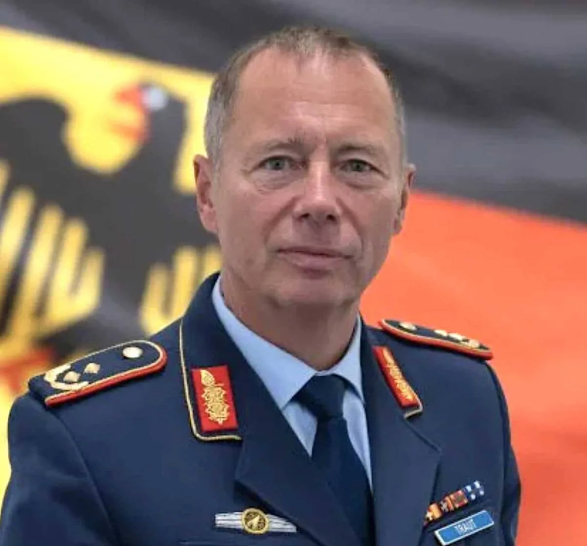 Major General Michael Traut in a blue German military uniform, looking directly forward against a German flag background.